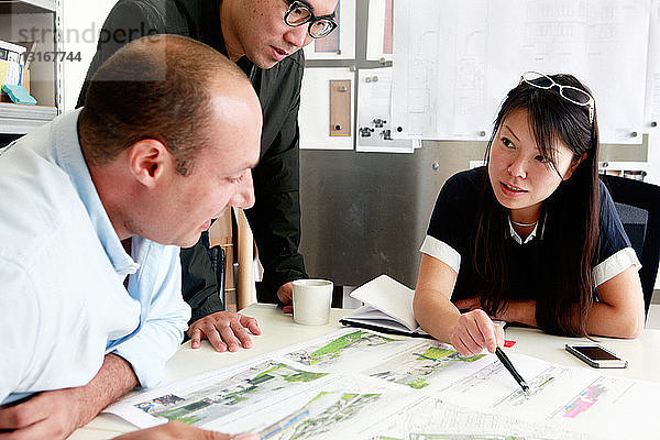 Team von drei Architekten diskutiert Ideen für den Entwurf im Büro