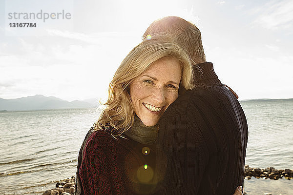 Ausgewachsenes Paar am See  umarmend  lächelnd