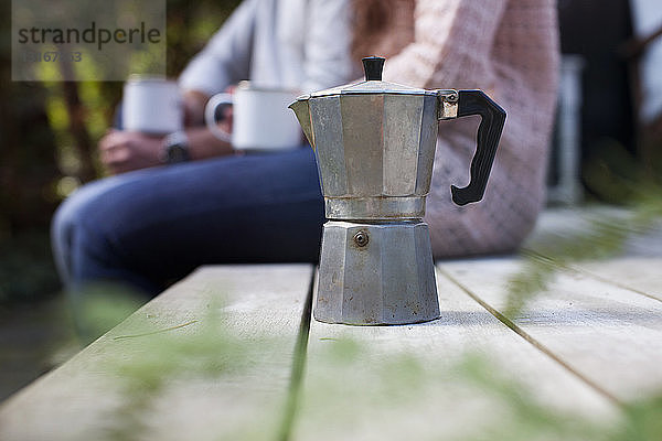 Schnappschuss eines auf der Gartenveranda sitzenden Paares mit Kaffeekanne