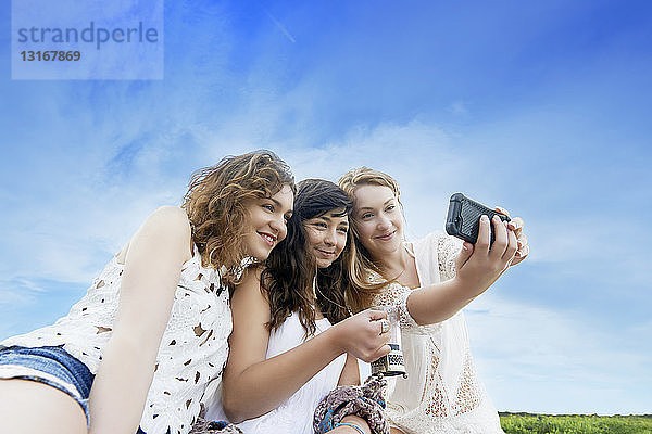 Drei junge Frauen im Feld posieren für Selfie auf Smartphone