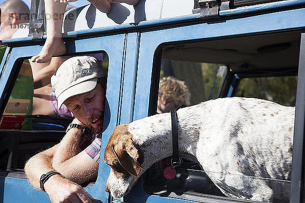 Erwachsener Mann und Hund lehnen sich aus dem Fenster eines Geländewagens  Lake Okareka  Neuseeland