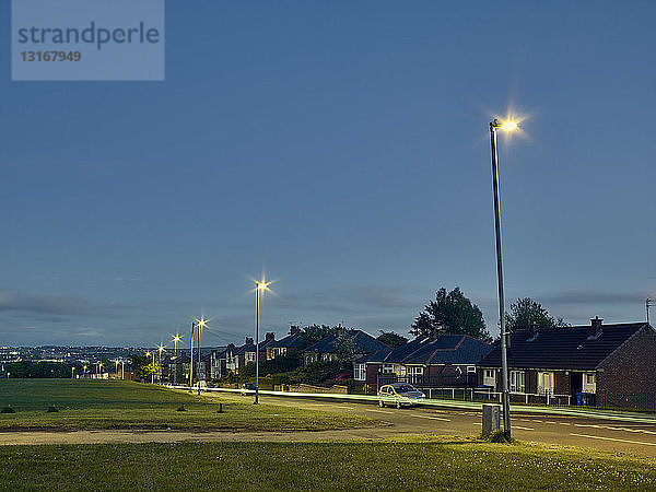 Lichtspuren auf der Straße bei Nacht in einem Wohngebiet