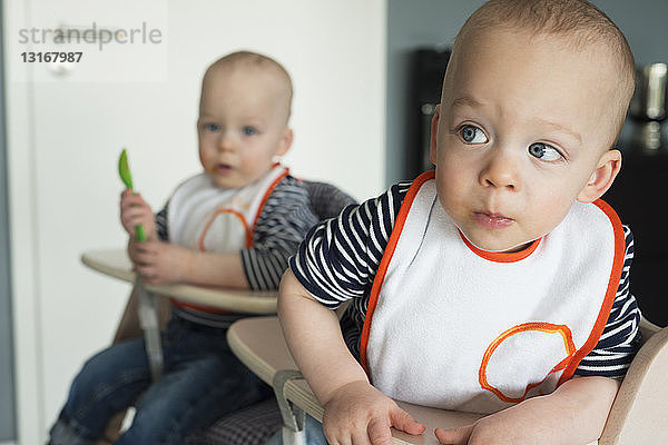 Kleine Zwillingsbrüder spielen auf Hochstühlen