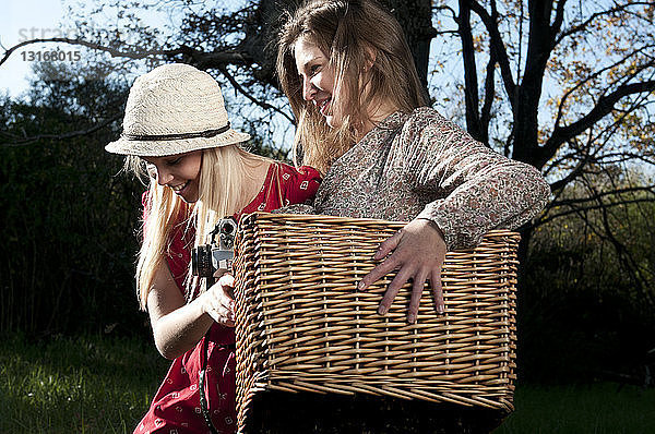 Junge Frauen tragen Picknickkorb