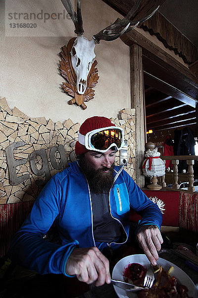 Mittelgroßer erwachsener männlicher Skifahrer  der im Restaurant isst  Tirol  Österreich