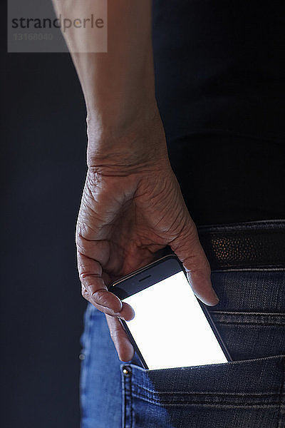 Frau entfernt Smartphone von Hand aus der Gesäßtasche