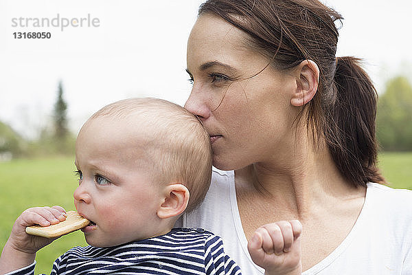 Porträt einer jungen Mutter  die ihren kleinen Sohn auf dem Feld küsst