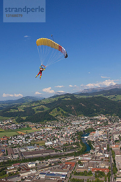Frau springt mit dem Fallschirm über ländlicher Landschaft ab