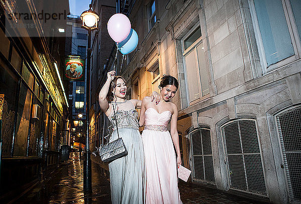Zwei Freundinnen in Abendkleidern amüsieren sich in der Stadt