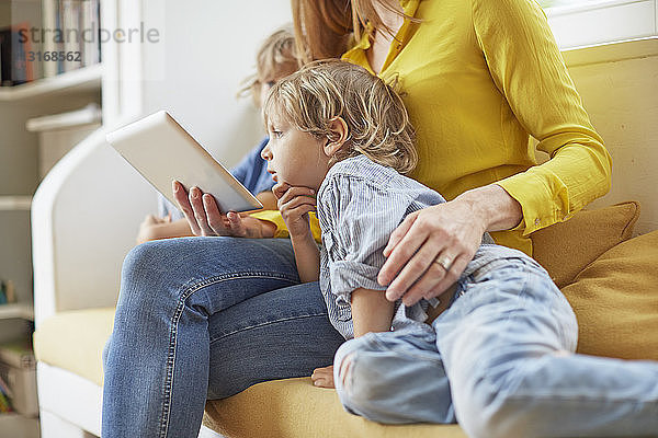 Mutter und zwei Söhne schauen auf das digitale Tablett  Mitte