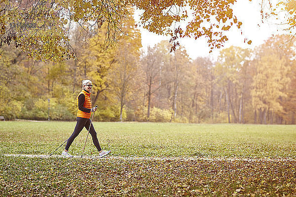 Senioren-Nordic-Walkerin beim Wandern auf dem Herbstparkweg
