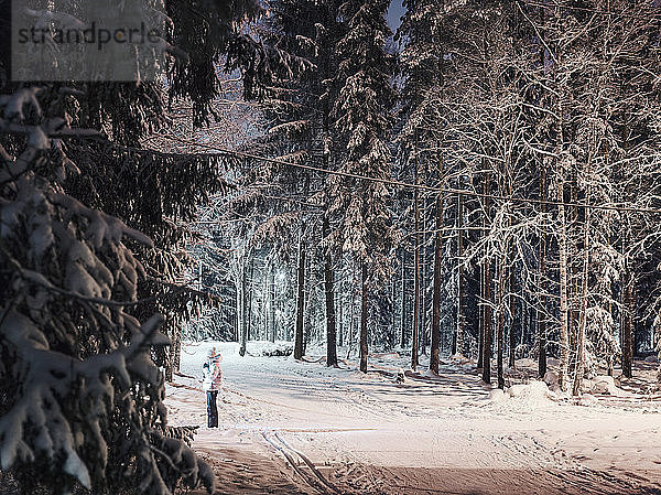 Mittelgrosse erwachsene Frau  die nachts auf einem Weg im verschneiten Wald steht  Lahti  Finnland