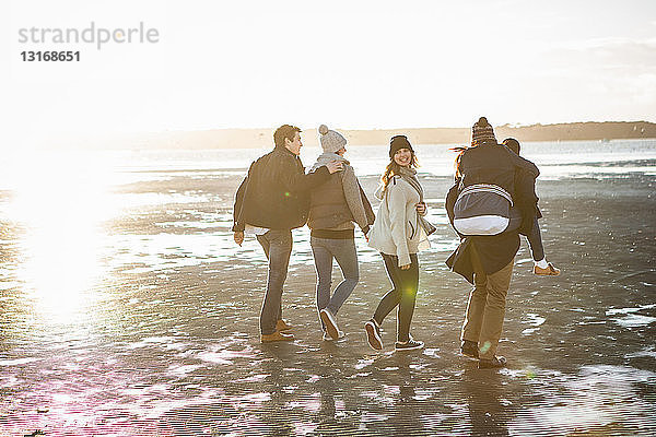 Fünf erwachsene Freunde gehen am Strand spazieren