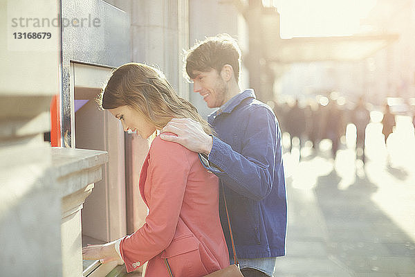 Ehepaar  das Geld am Geldautomaten auf der Straße abhebt  London  UK