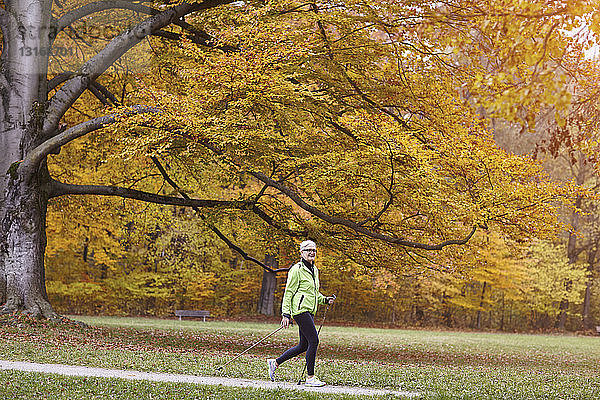 Seniorin beim Nordic Walking im Herbstpark