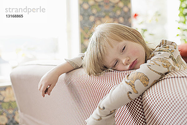 Porträt eines schläfrigen Jungen  der sich auf einem Wohnzimmersofa anlehnt