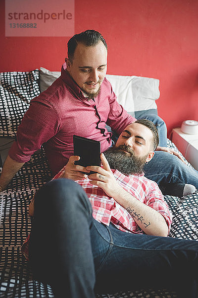 Schwules Paar benutzt Smartphone im Schlafzimmer