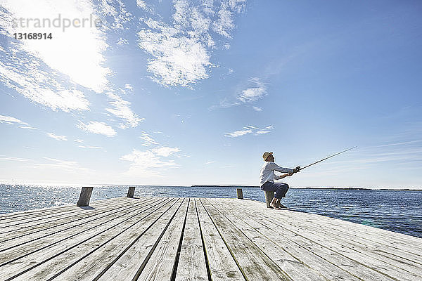 Mittelgroßer erwachsener Mann beim Angeln vor dem Pier  Utvalnas  Schweden