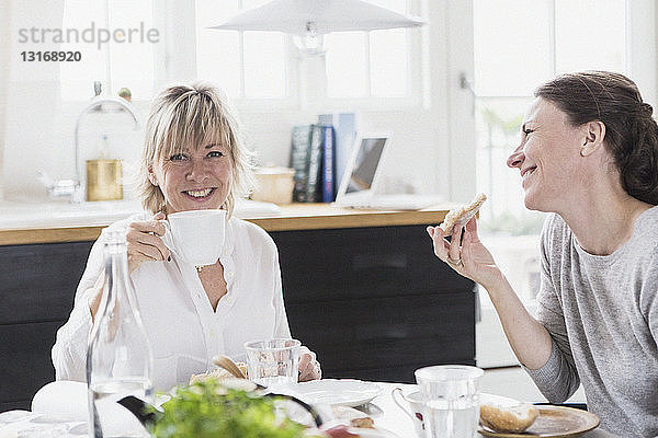 Zwei reife Frauen sitzen am Küchentisch und trinken Tee