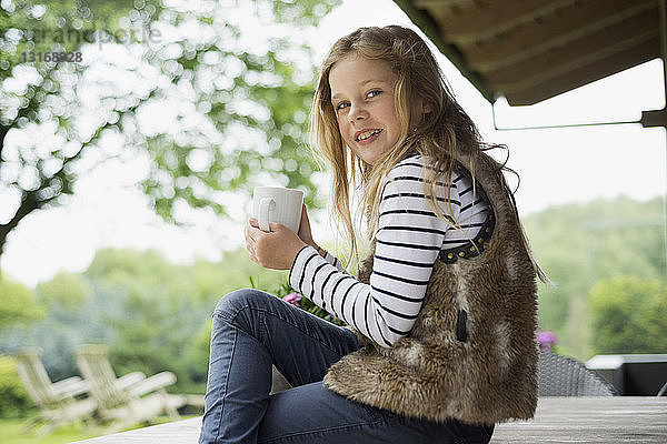 Mädchen sitzt und hält Becher