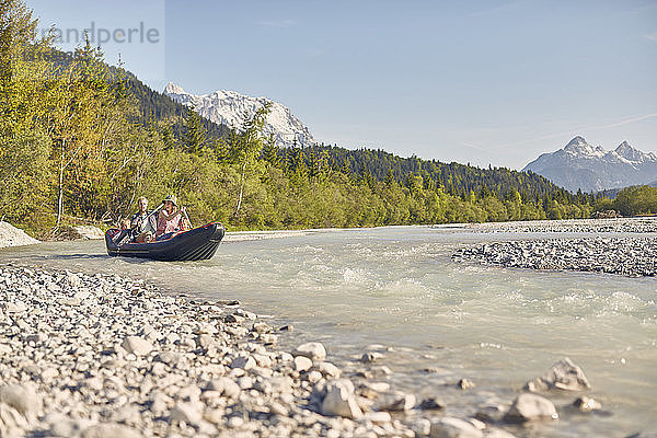 Familie benutzt Paddel zum Steuern eines Schlauchbootes auf dem Wasser  Wallgau  Bayern  Deutschland