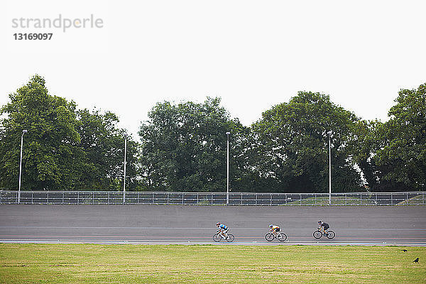 Drei Radfahrer auf der Radrennbahn des Velodroms  im Freien