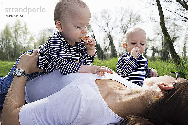 Zwillingsbrüder und Mutter picknicken auf dem Feld