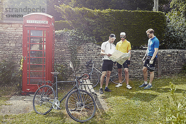 Radfahrer Kartenlesen durch rote Telefonzelle  Cotswolds  UK