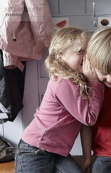 Mädchen flüstert einem Jungen ins Ohr