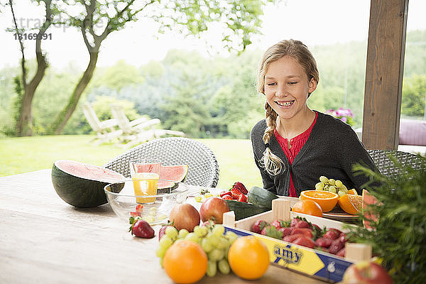 Mädchen am Terrassentisch mit einer Auswahl an frischem Obst