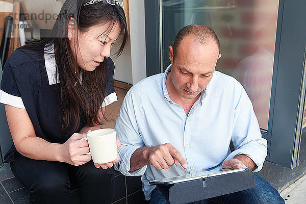 Zwei Architektenkollegen verwenden ein digitales Tablett auf einer Bürostufe