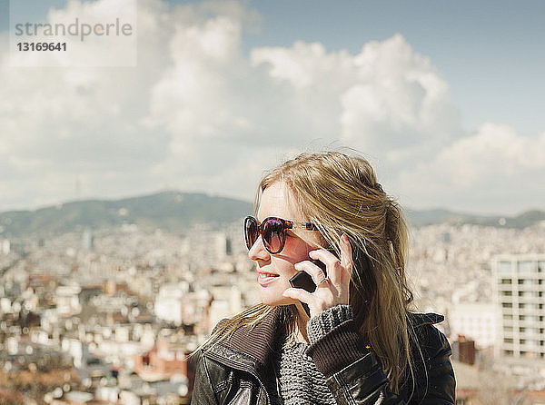 Touristin spricht auf einem Smartphone vor dem Stadtbild vom Montjuic-Hügel  Barcelona  Spanien