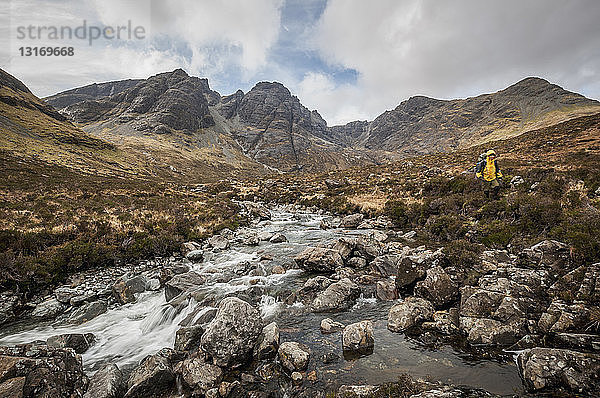 Wanderer an einem Fluss mit dem Black Cuillin's ''Bla Bheinn'' Mountain  Isle of Skye  Schottland