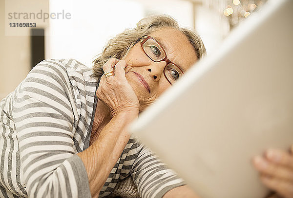 Ältere Frau liest mit digitalem Tablett