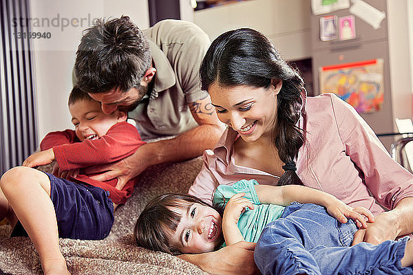 Familie mit zwei Kindern  die auf dem Sofa spielen