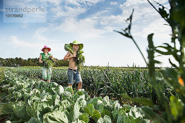 Mutter und Tochter tragen Gemüse auf dem Feld