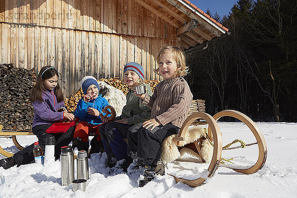 Kinder mit Brezelpause und warmem Getränk im Schnee