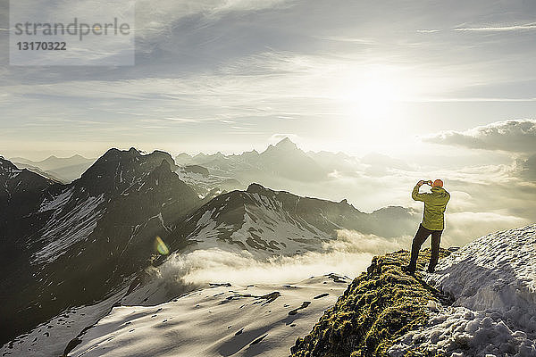 Junger männlicher Bergwanderer fotografiert Wolkenansichten  Bayerische Alpen  Oberstdorf  Bayern  Deutschland