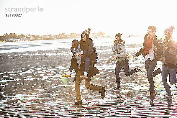 Fünf erwachsene Freunde laufen am Strand