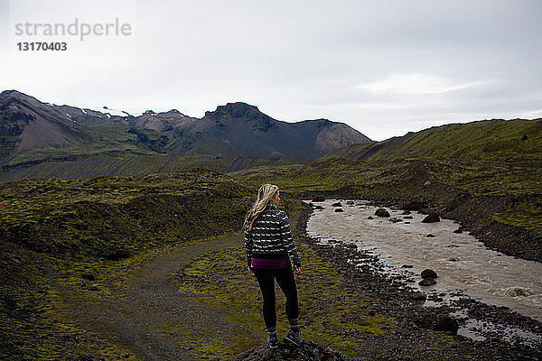 Rückansicht einer mittleren erwachsenen Frau am Fluss mit Blick auf die Bergkette  Island