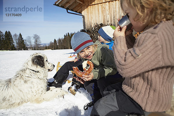 Kinder mit Brezelpause und warmem Getränk im Schnee