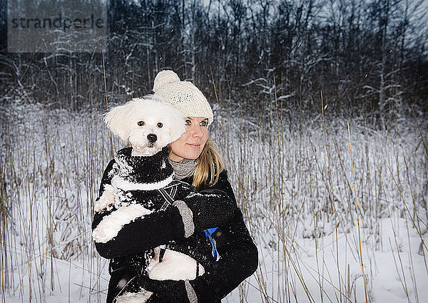 Mittlere erwachsene Frau mit Haushund in verschneiter Landschaft