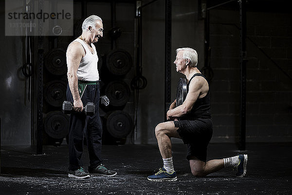 Ältere Männer bereiten sich in dunkler Turnhalle auf das Gewichtheben vor