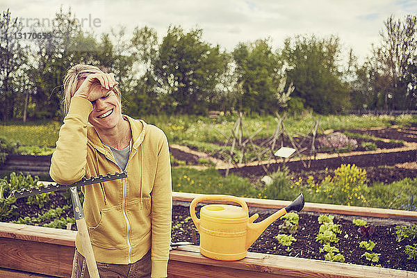 Reife Frau  Gartenarbeit  auf Rechen lehnend  lachend