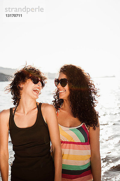 Lachende Frauen mit Sonnenbrille am Strand