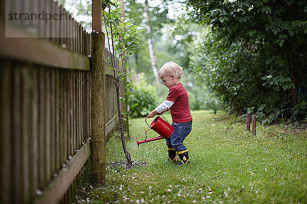 Kleinkind Junge gießt Pflanzen im Garten