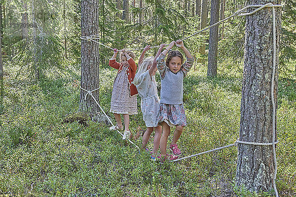 Mädchen in Retro-Kleidung balancieren auf Seilen im Wald