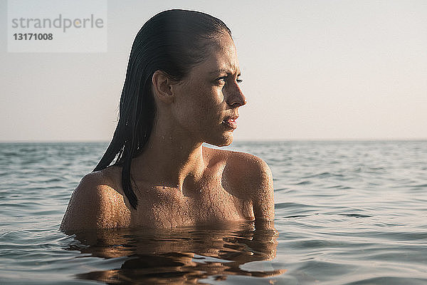 Porträt einer jungen Frau mit nackten Schultern im Meer