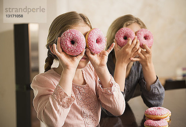 Porträt von zwei Schwestern mit Doughnut-Löchern über den Augen