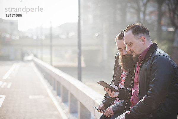 Schwules Paar mit Smartphone auf dem Bürgersteig